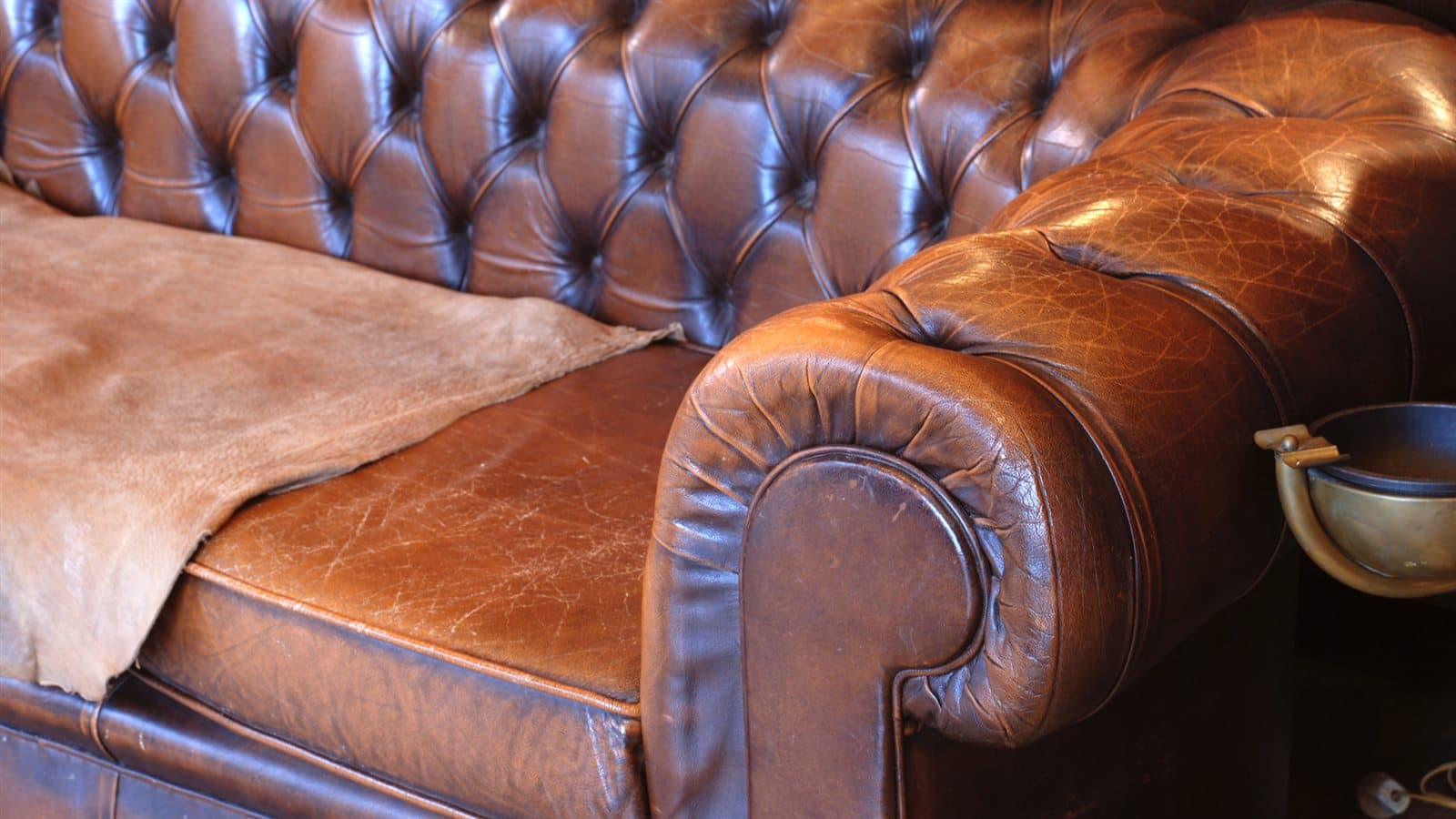 Close view of worn brown tufted leather and a loose leather hide